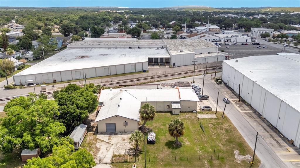 An aerial view shows a small building with a metal roof next to large warehouses — 400 NW PHOSPHATE BOULEVARD, MULBERRY, FL