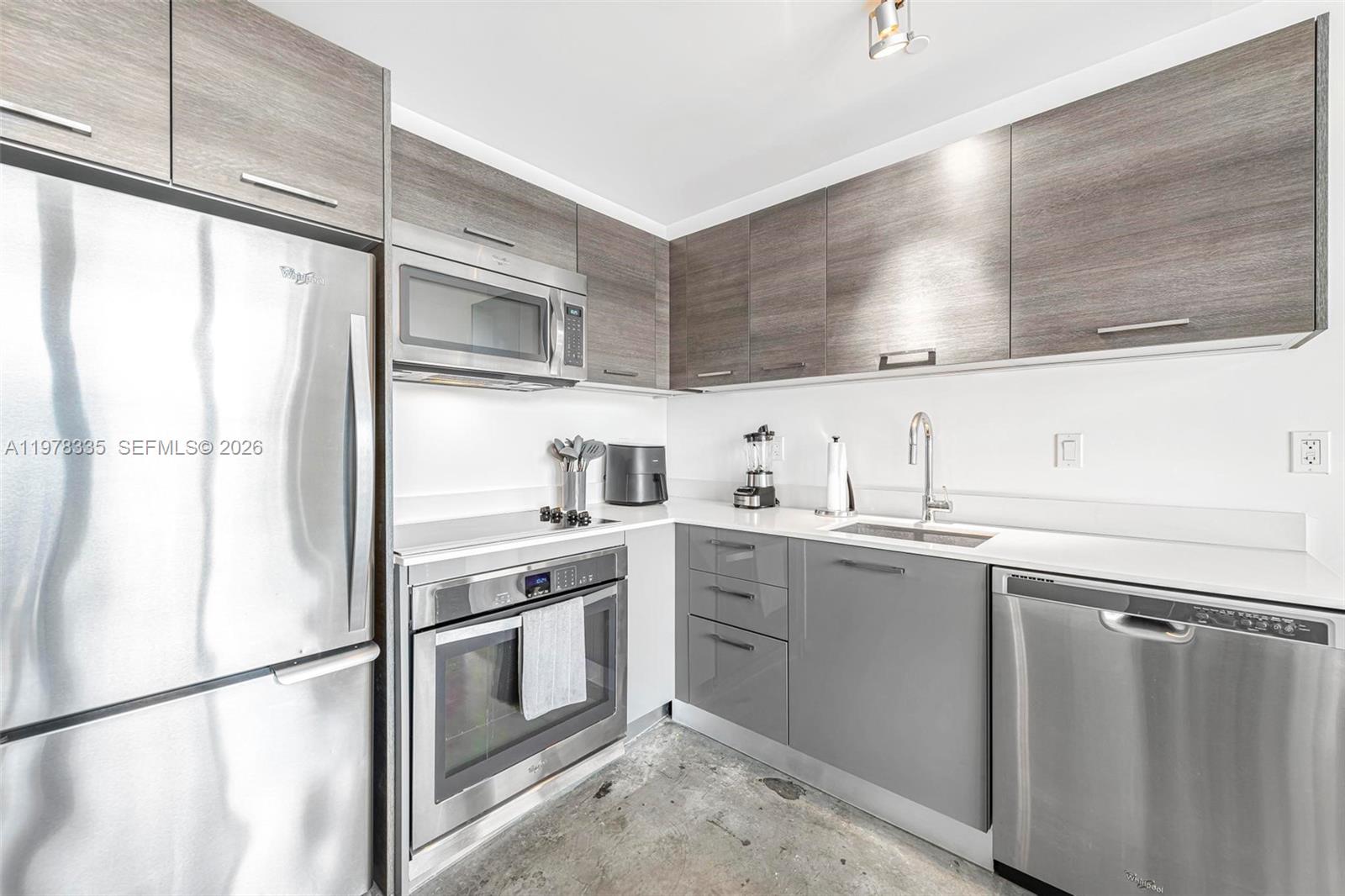 A modern kitchen features stainless steel appliances, grey cabinetry, and a concrete floor — 151 SE 1st St # 2409, Miami FL 33131, MIAMI, FL