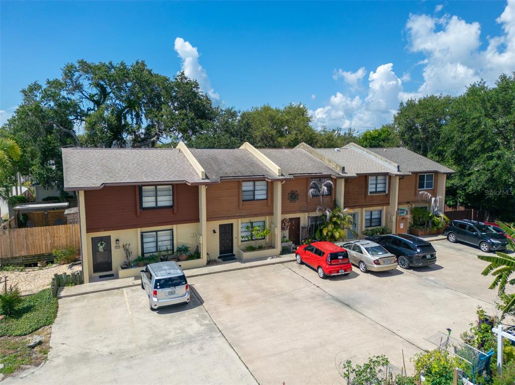 An exterior view of a multi-unit townhouse complex with a shared concrete parking lot — 117 HARBOR DRIVE, CAPE CANAVERAL, FL