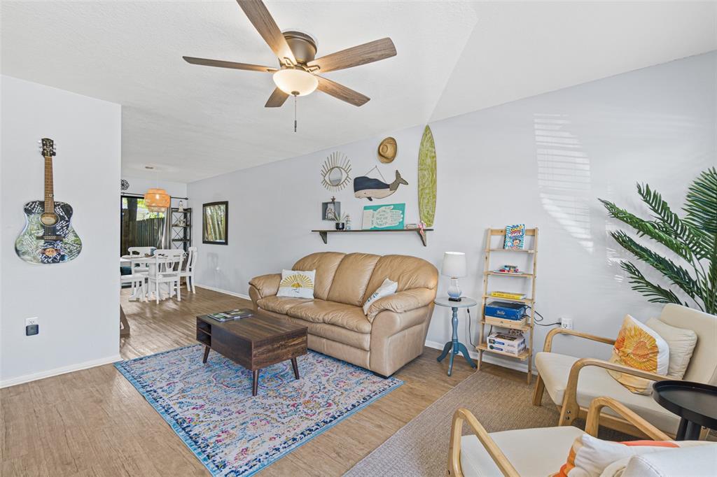 A living room features a tan leather sofa, a patterned rug, and a ceiling fan — 117 HARBOR DRIVE, CAPE CANAVERAL, FL