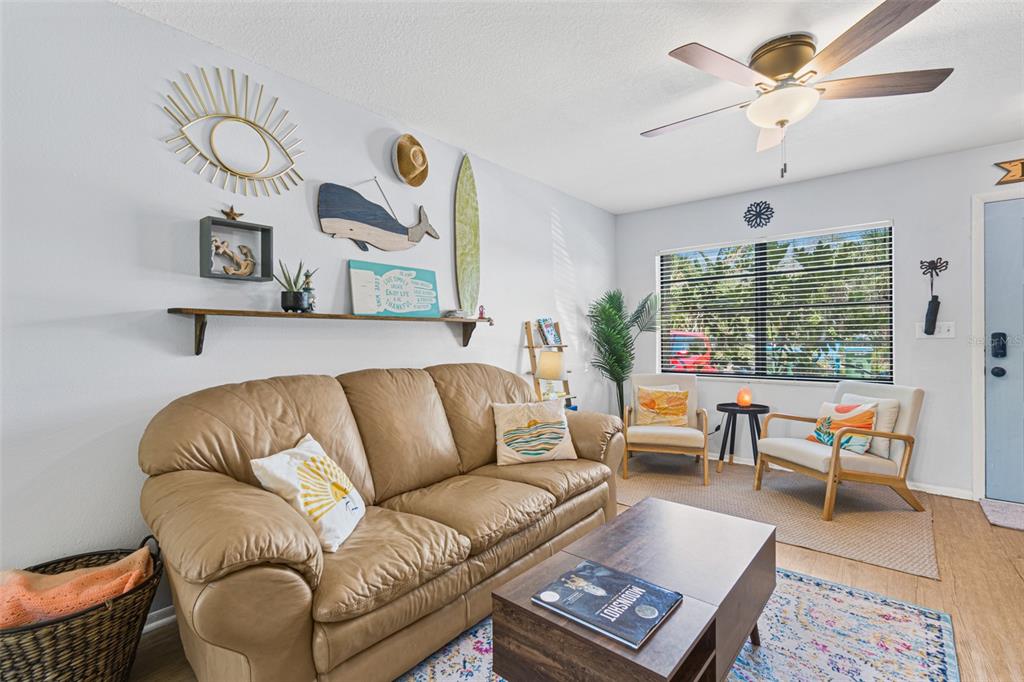 A living room features a tan leather sofa, a wooden coffee table, and coastal wall decor — 117 HARBOR DRIVE, CAPE CANAVERAL, FL