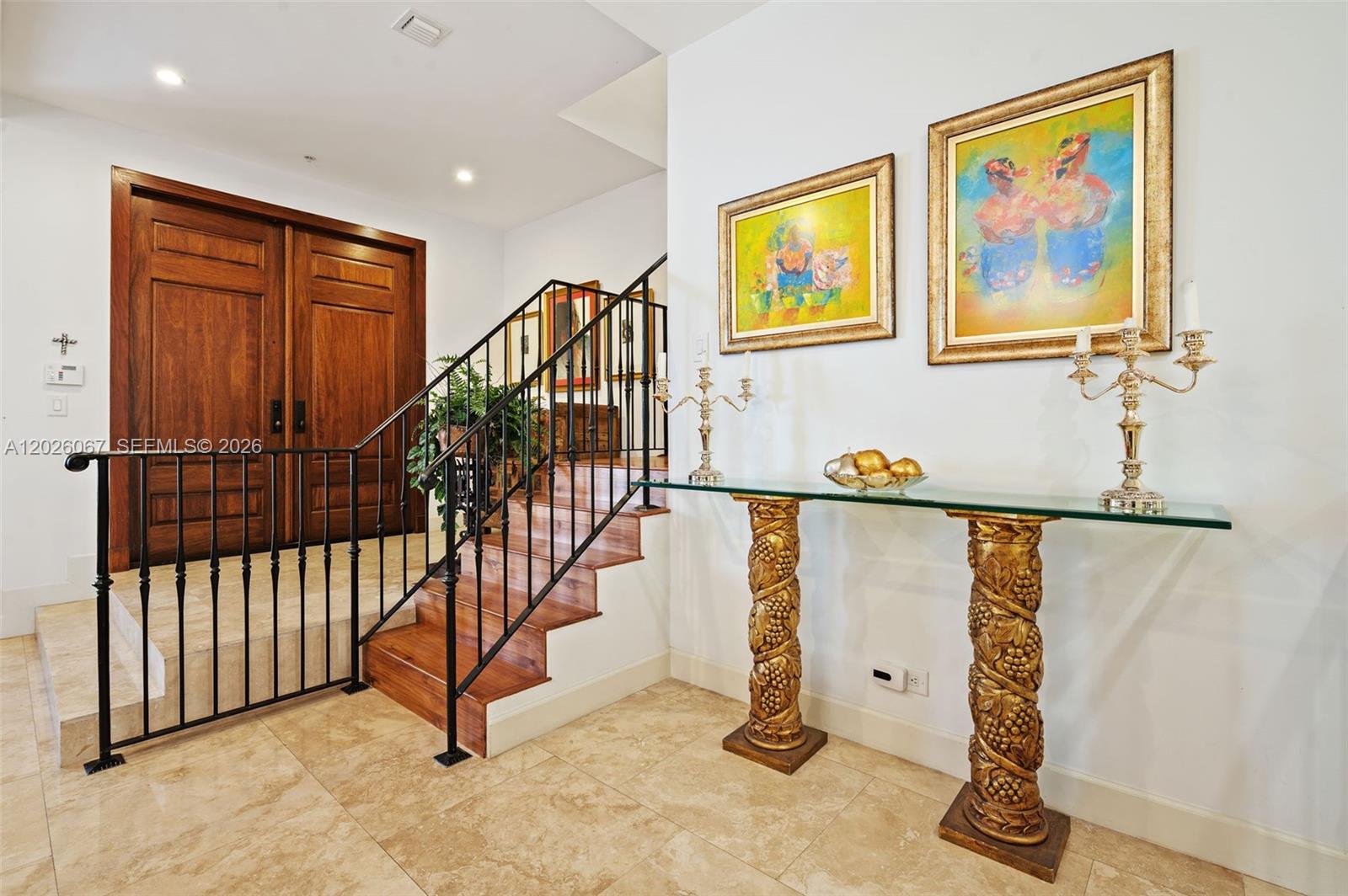 An entryway features a wooden staircase with a black railing, tile flooring, and a console table — 7510 SW 56th Ct, Miami FL 33143, MIAMI, FL