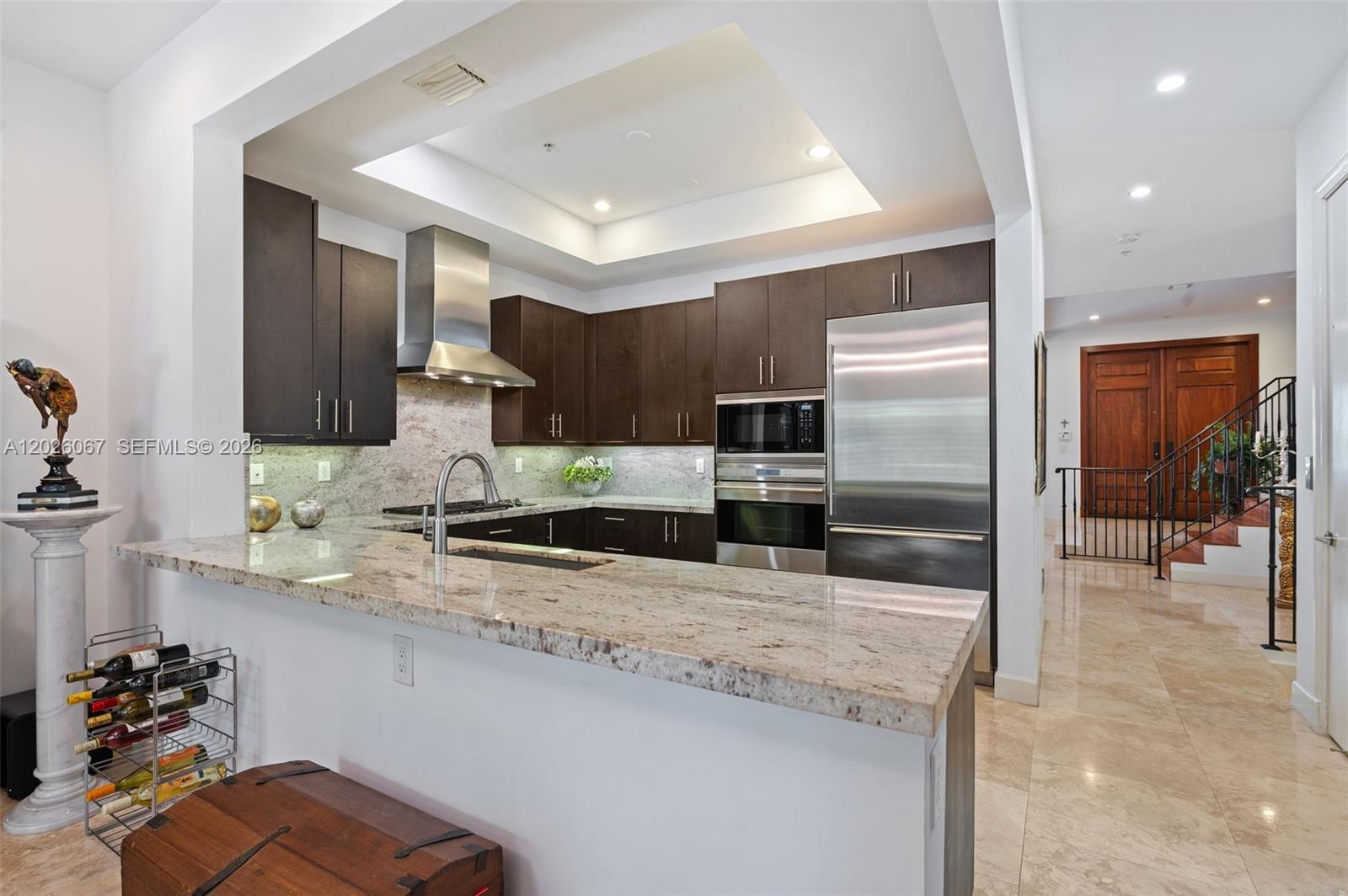 A kitchen features dark wood cabinets, granite countertops, stainless steel appliances, and a breakfast bar — 7510 SW 56th Ct, Miami FL 33143, MIAMI, FL