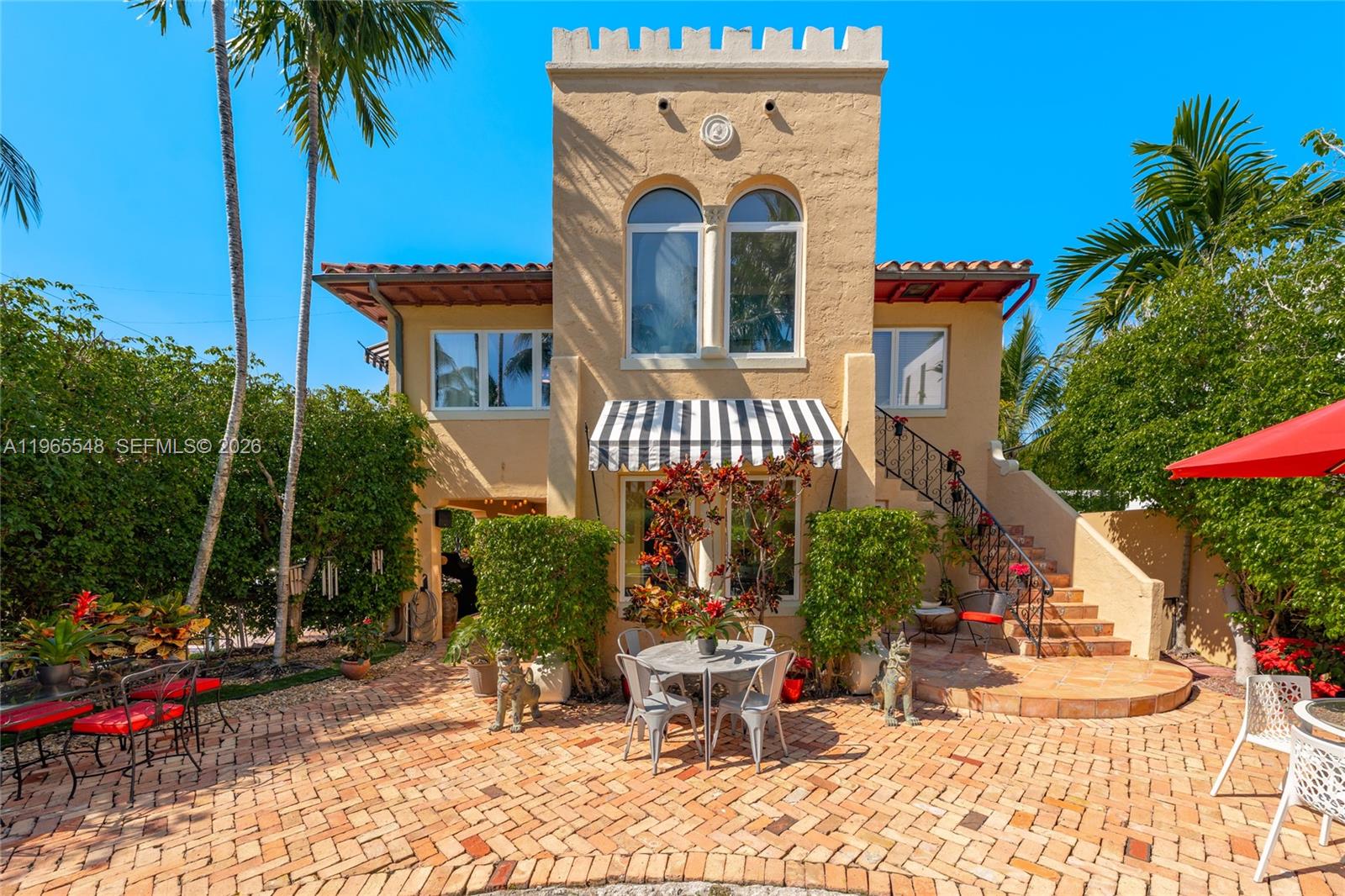 A two-story stucco house with a crenellated tower, striped awning, and brick patio — 4500 Sheridan Ave, Miami Beach FL 33140, MIAMI BEACH, FL