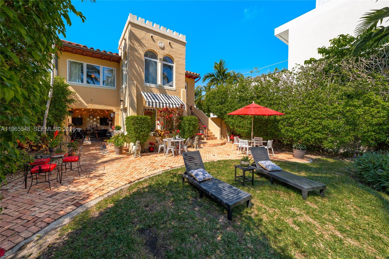 A backyard patio features brick pavers, lounge chairs, a red umbrella, and a stucco house — 4500 Sheridan Ave, Miami Beach FL 33140, MIAMI BEACH, FL