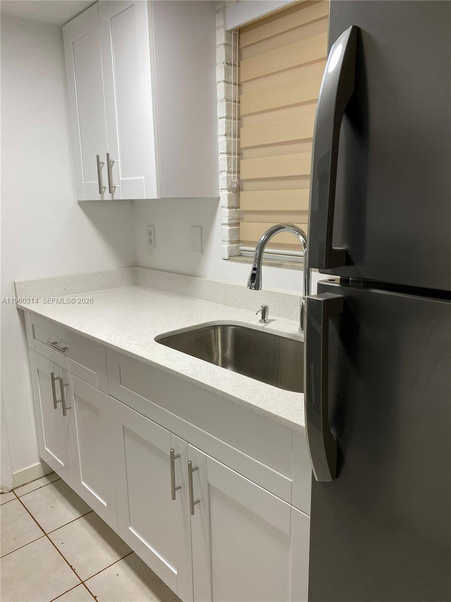 A kitchen features white cabinets, a light-colored countertop, a stainless steel sink, and a refrigerator — 12500 NE 5th Ave # 101, North Miami FL 33161, NORTH MIAMI, FL