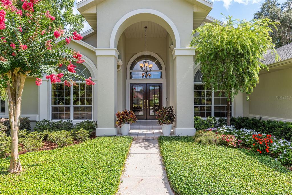 The exterior of a house features a covered entryway with double doors and arched windows — 2215 SE SPRING HILL COURT, OCALA, FL
