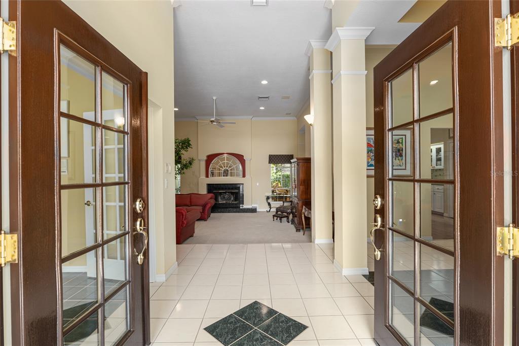 A view through open double doors into a tiled foyer leading to a carpeted living room — 2215 SE SPRING HILL COURT, OCALA, FL
