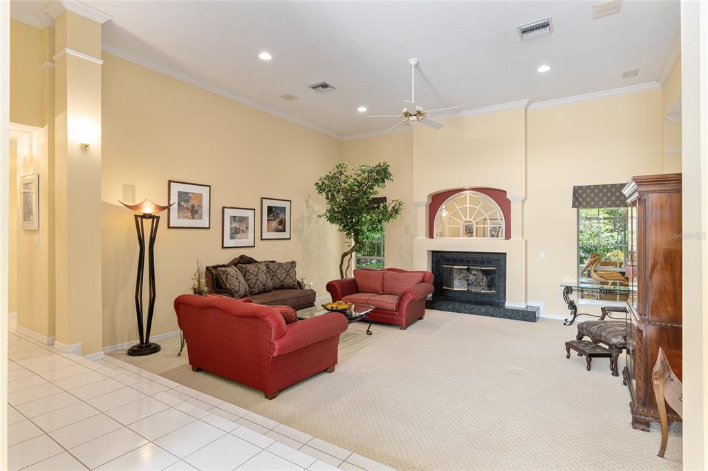 A living room with high ceilings, a fireplace, red sofas, and light-colored carpeting — 2215 SE SPRING HILL COURT, OCALA, FL