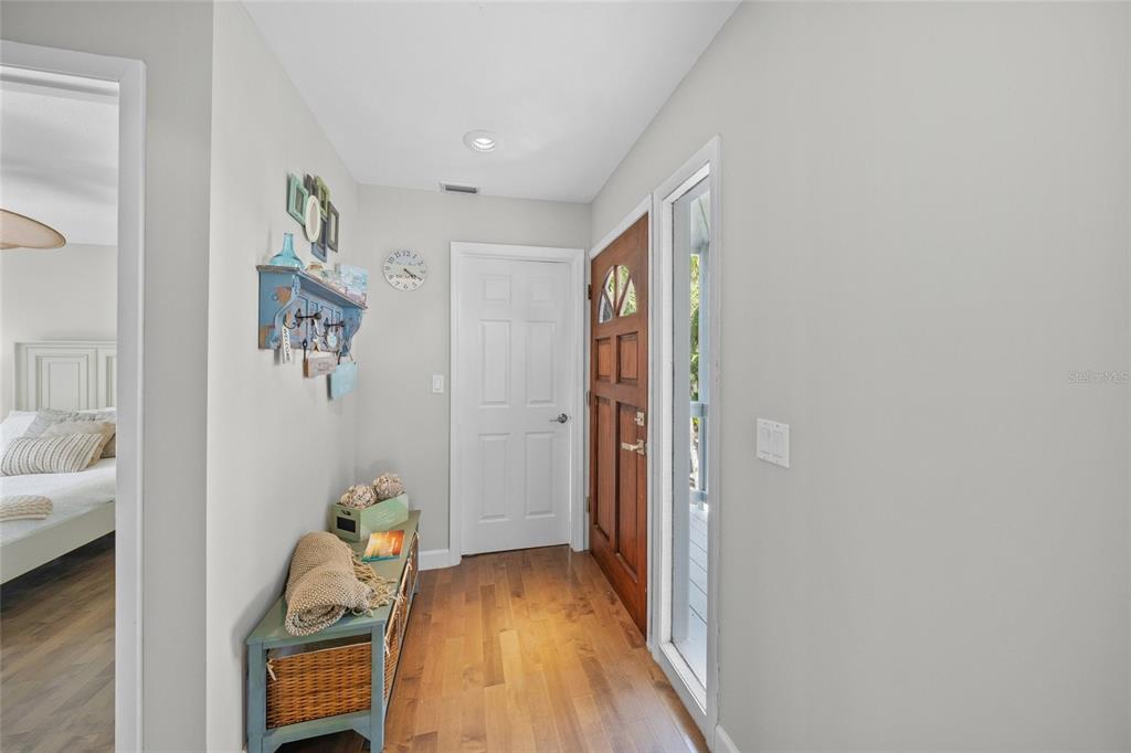 A bright entryway features hardwood floors, a wooden front door, and a blue storage bench — 1256 RIEGELS LANDING DRIVE, SARASOTA, FL