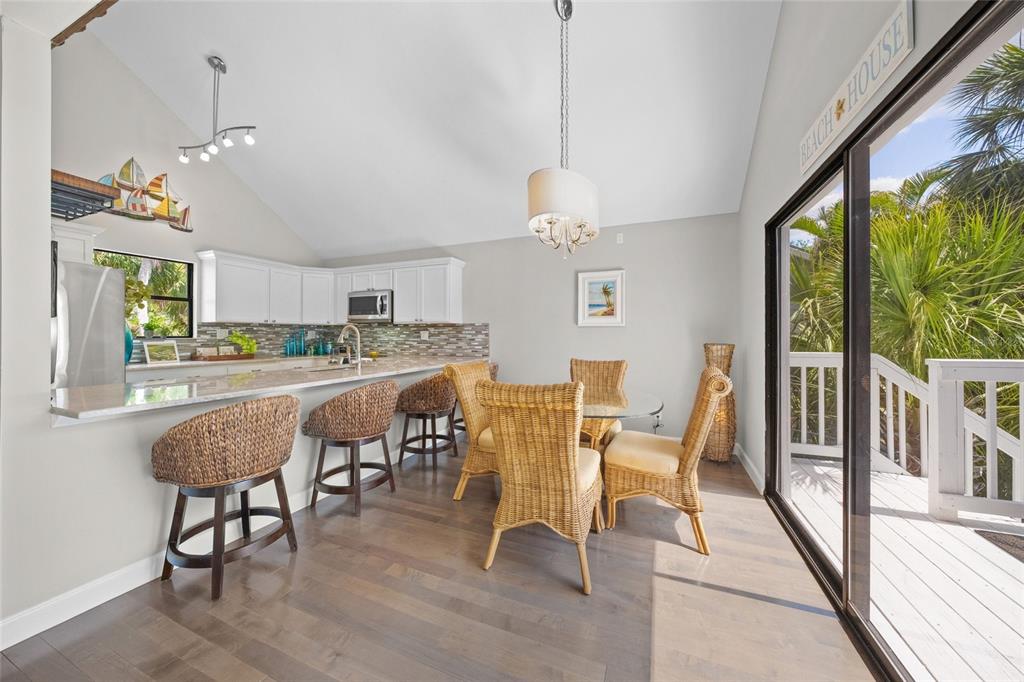 A kitchen and dining area with wicker chairs, white cabinets, and a sliding glass door — 1256 RIEGELS LANDING DRIVE, SARASOTA, FL