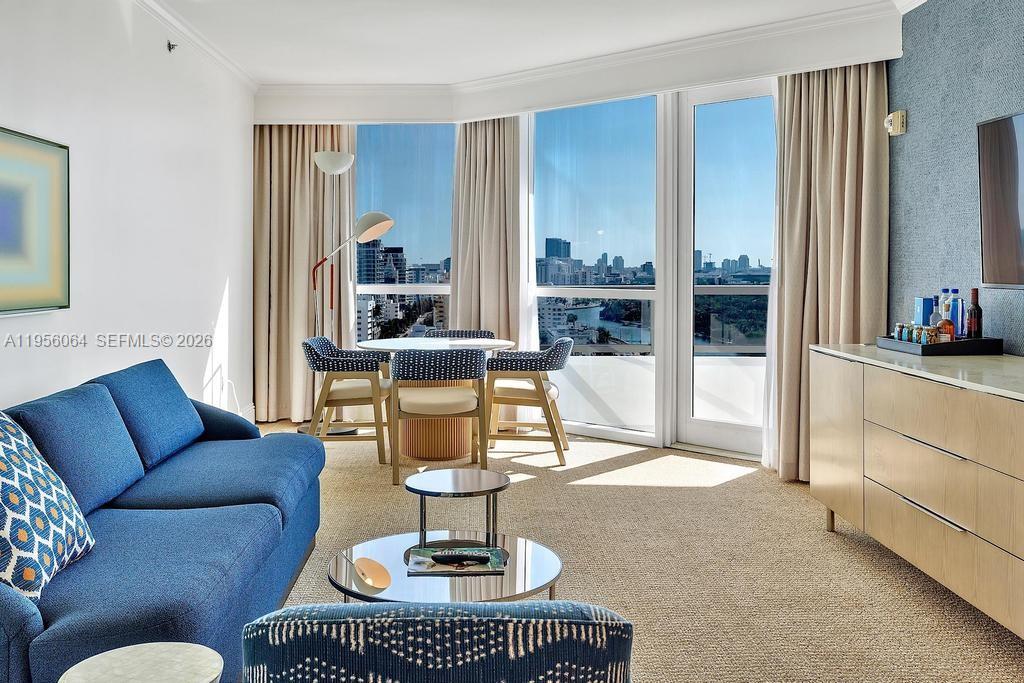 A living room features a blue sofa, a dining set, and floor-to-ceiling windows with views — 4401 Collins Ave # 1712, Miami Beach FL 33140, MIAMI BEACH, FL