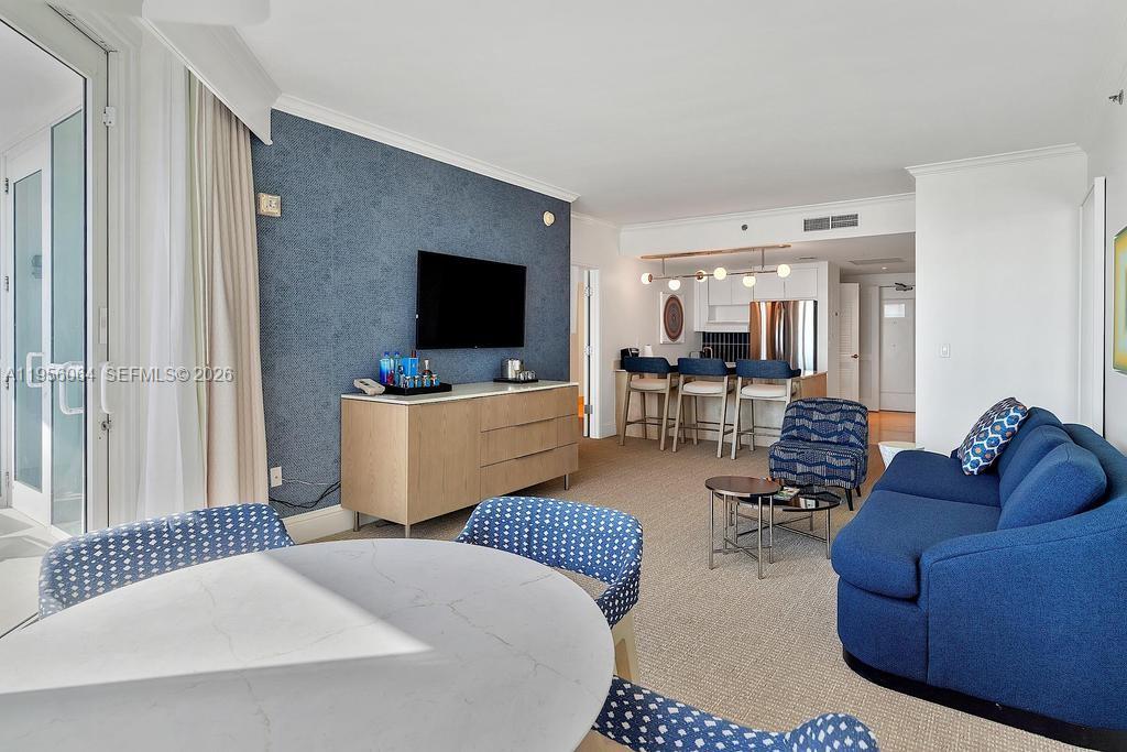 A living room features a blue accent wall, a television, a sofa, and a kitchen — 4401 Collins Ave # 1712, Miami Beach FL 33140, MIAMI BEACH, FL