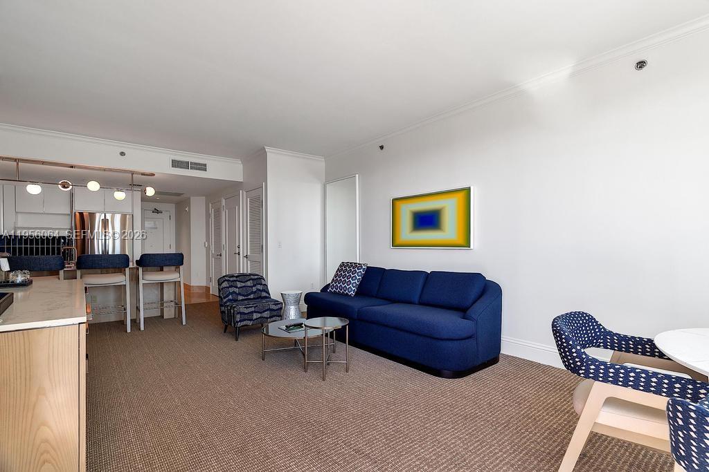 A living room features a blue sofa, patterned armchair, and an open kitchen with barstools — 4401 Collins Ave # 1712, Miami Beach FL 33140, MIAMI BEACH, FL