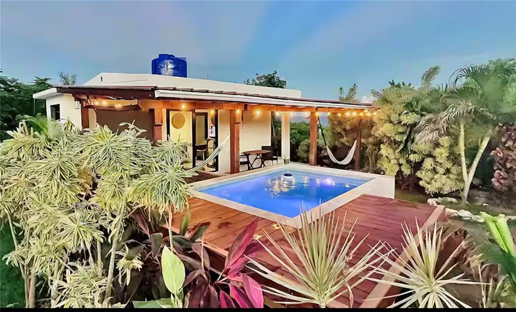 A small house with a wooden deck and a swimming pool surrounded by tropical plants — COZY CASITAS-PUNTAS- CALLE VISTA DEL MAR, RINCON, PR