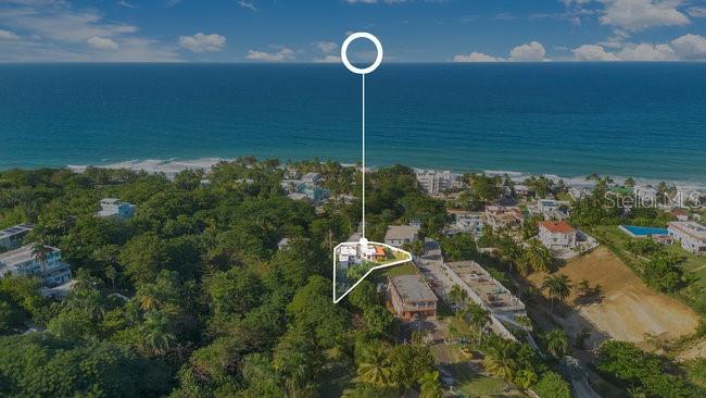 An aerial view shows a house highlighted by a white outline near a coastal beach — COZY CASITAS-PUNTAS- CALLE VISTA DEL MAR, RINCON, PR