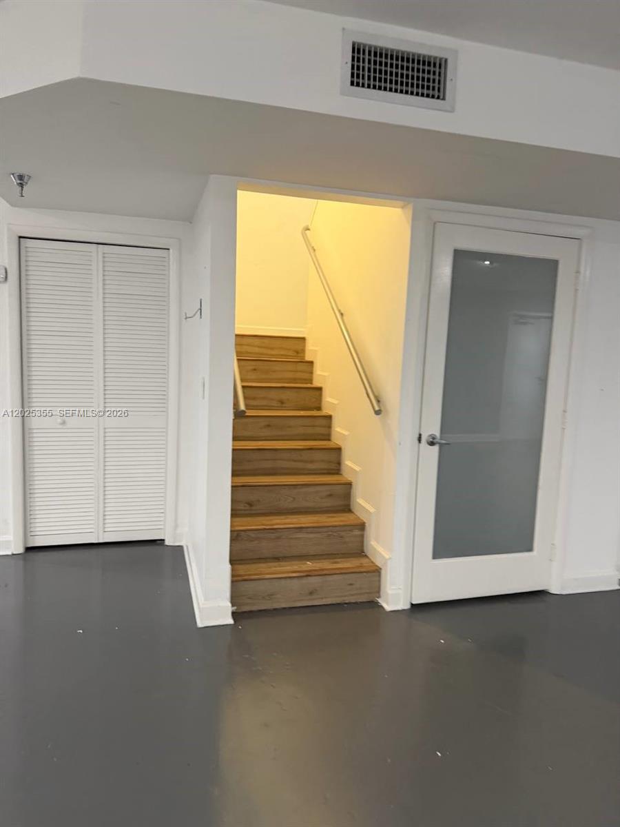 A staircase with wood-look treads sits between a louvered closet door and a glass door — 3002 NW 79th Ave # 3002, Doral FL 33122, DORAL, FL