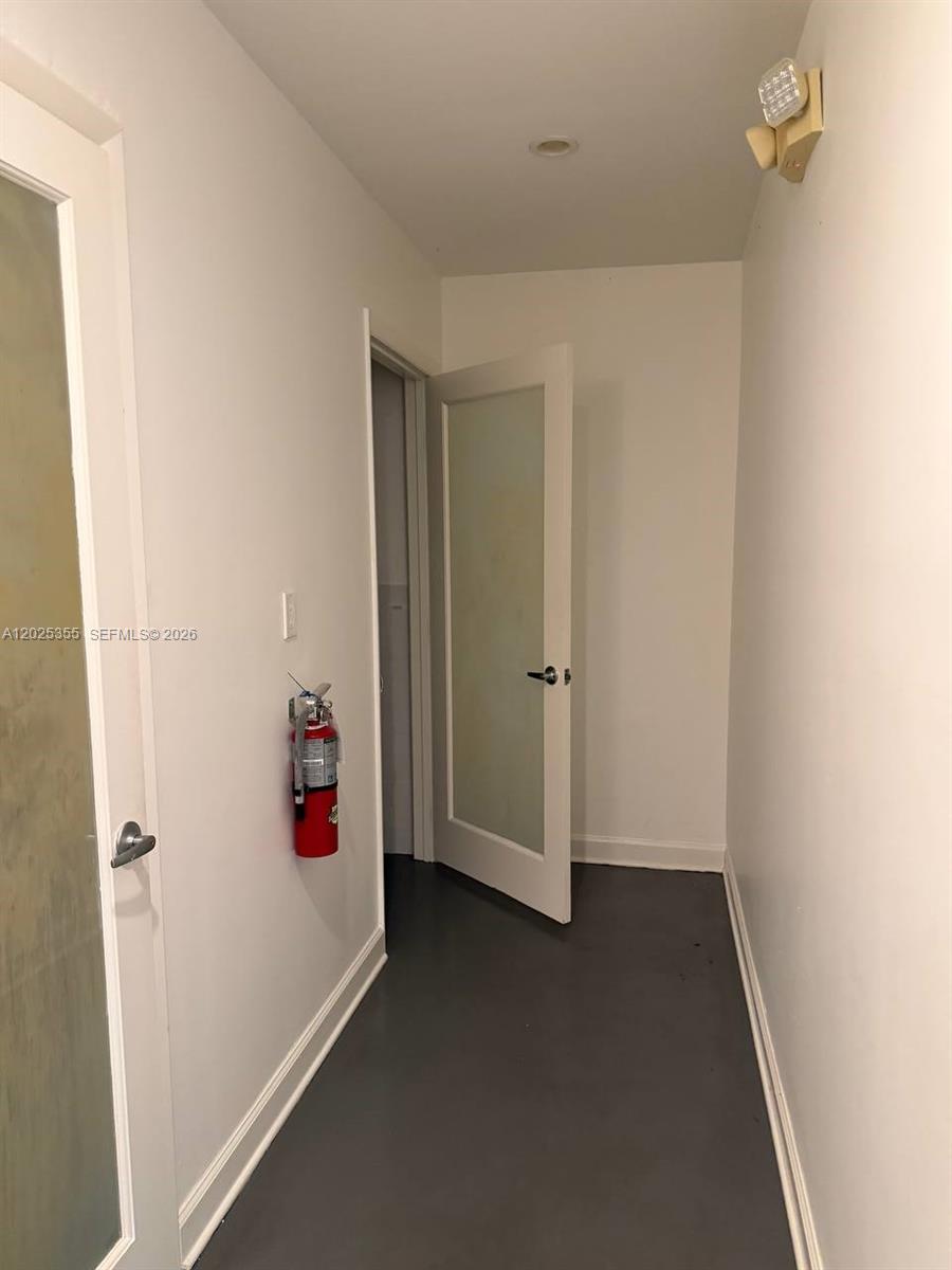 A hallway features white walls, a gray floor, a fire extinguisher, and a glass-paneled door — 3002 NW 79th Ave # 3002, Doral FL 33122, DORAL, FL