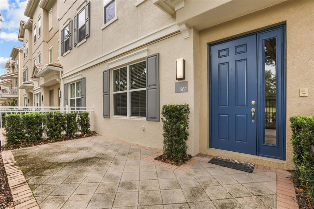 A blue front door with a side light opens onto a paved patio area — 661 HANGNEST LANE, LAKE MARY, FL