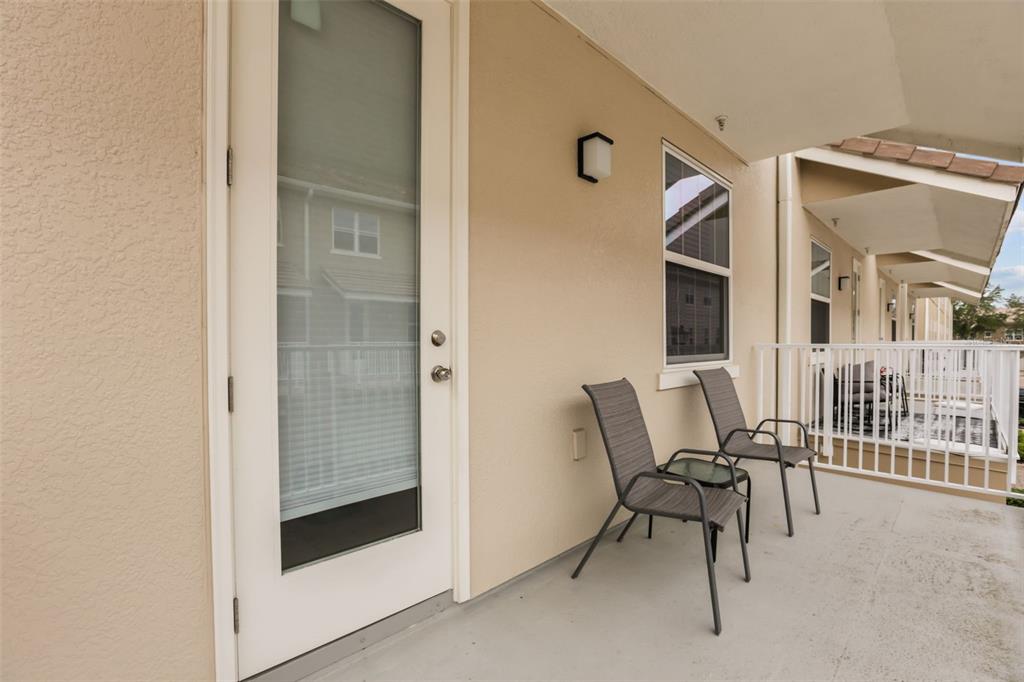 A covered balcony features two chairs, a glass door, and a white railing — 661 HANGNEST LANE, LAKE MARY, FL