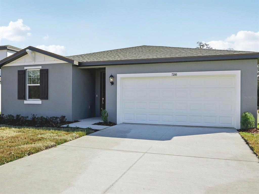 A single-story house with a gray exterior, a white garage door, and a concrete driveway — 7200 RAY CREEK DRIVE, BROOKSVILLE, FL