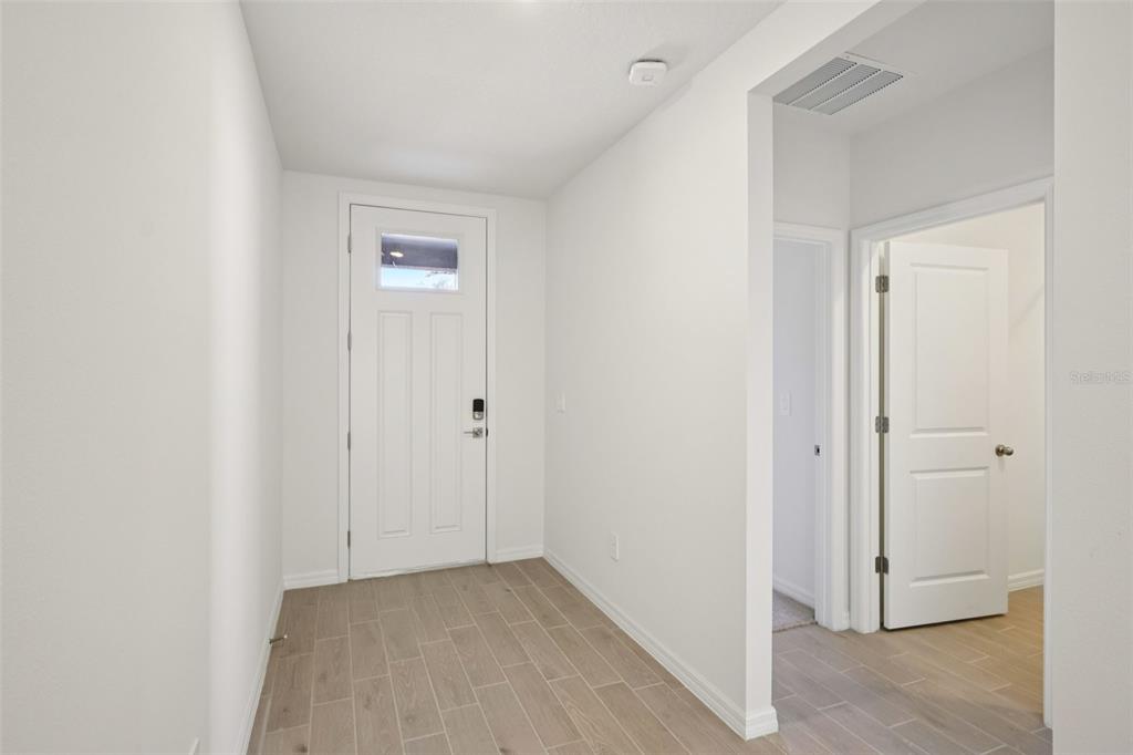 An entryway with a white front door, light wood-look tile flooring, and white walls — 7200 RAY CREEK DRIVE, BROOKSVILLE, FL