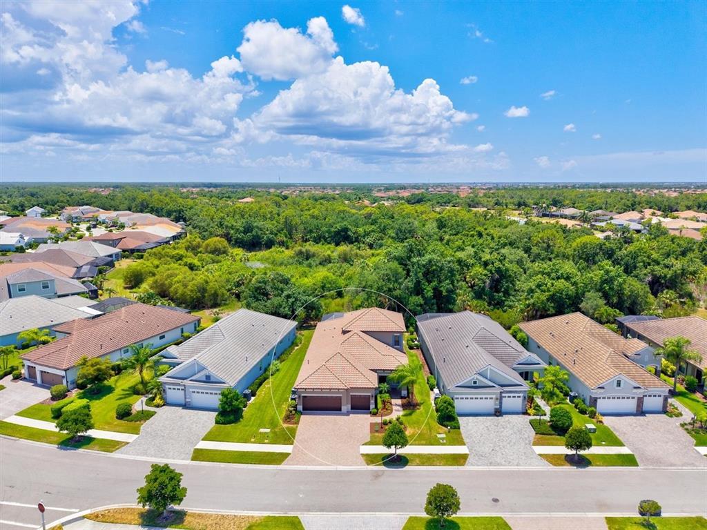 An aerial view shows a suburban house with a tiled roof and a paved driveway — 11909 HUNTERS CREEK ROAD, VENICE, FL