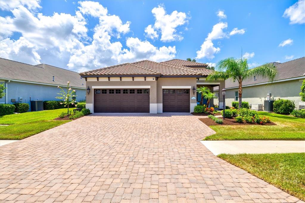 A single-story house with a paved driveway, two garage doors, and a tiled roof — 11909 HUNTERS CREEK ROAD, VENICE, FL