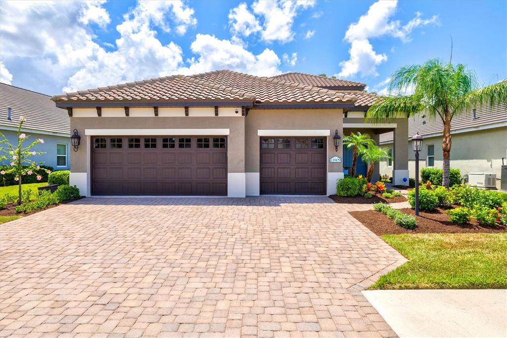 A single-story house with a two-car garage, tile roof, and a paved driveway — 11909 HUNTERS CREEK ROAD, VENICE, FL