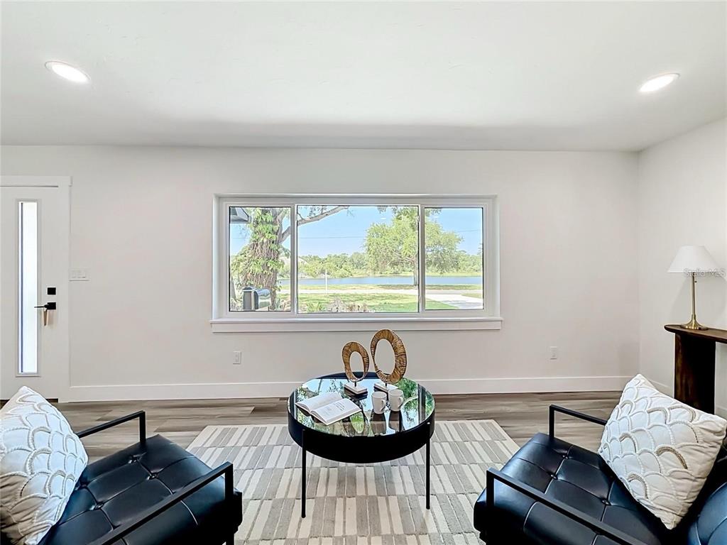 A living room features two black leather chairs, a glass coffee table, and a large window — 2335 MURILLA WAY S, ST PETERSBURG, FL