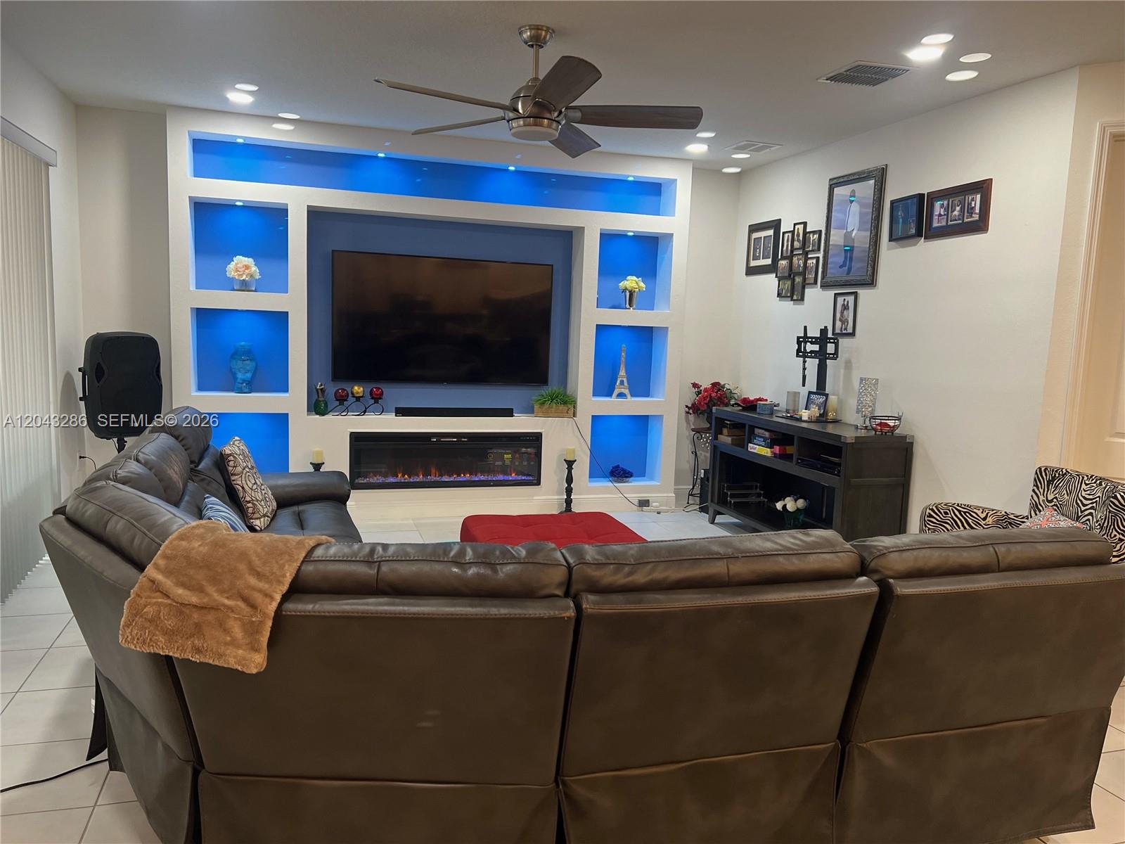 A living room features a large sectional sofa facing a built-in wall unit with blue lighting — 3855 Carrick Bend Dr, Kissimmee FL 34746, KISSIMMEE, FL