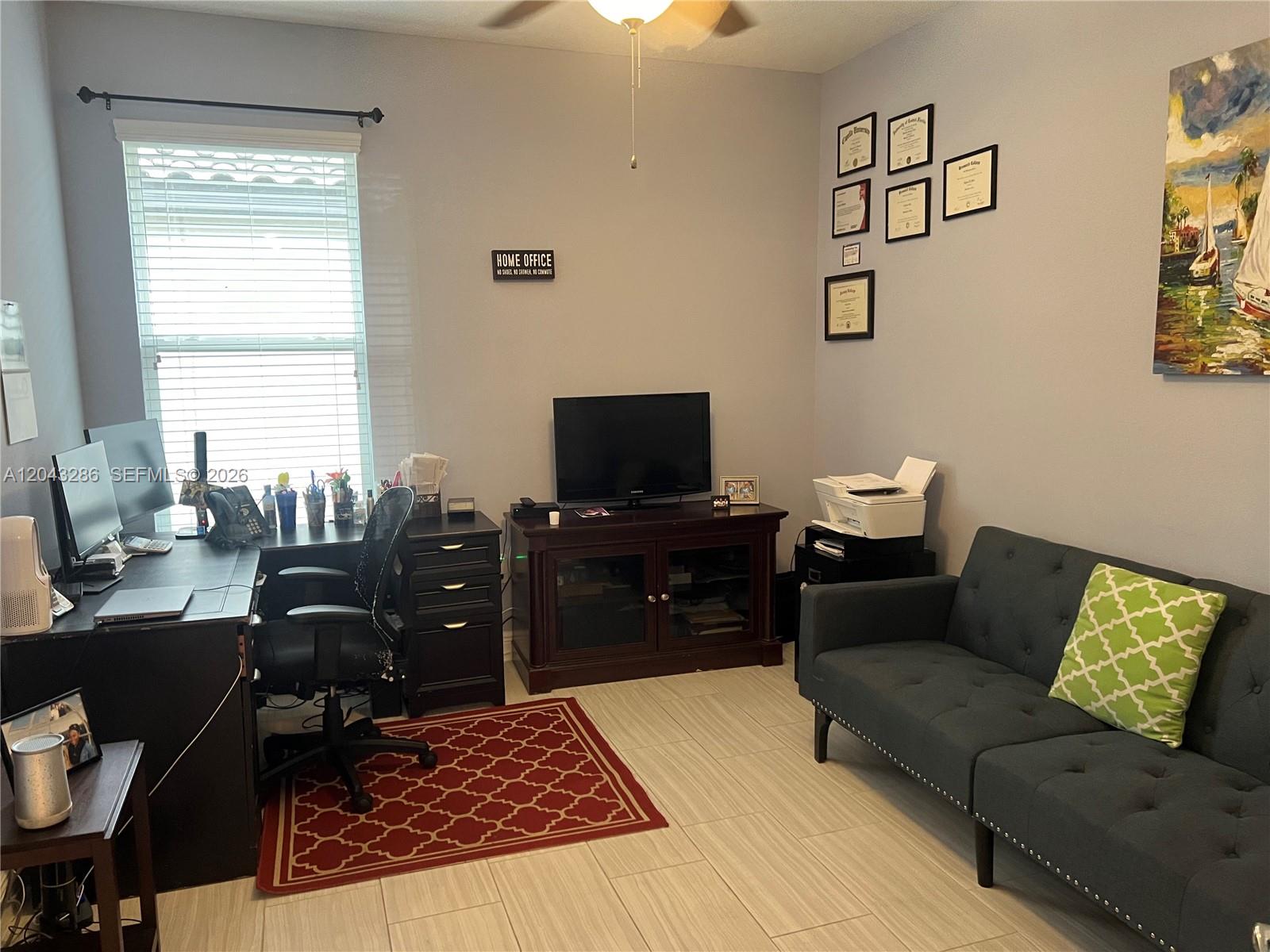 A home office features a desk, television console, sofa, and framed wall decor on tile floors — 3855 Carrick Bend Dr, Kissimmee FL 34746, KISSIMMEE, FL