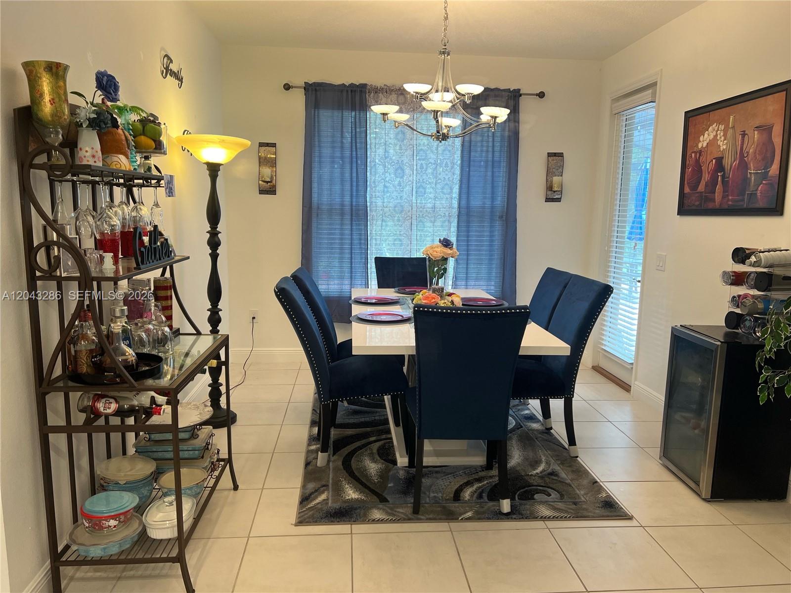 A dining room features a white table, blue upholstered chairs, a metal shelving unit, and chandelier — 3855 Carrick Bend Dr, Kissimmee FL 34746, KISSIMMEE, FL