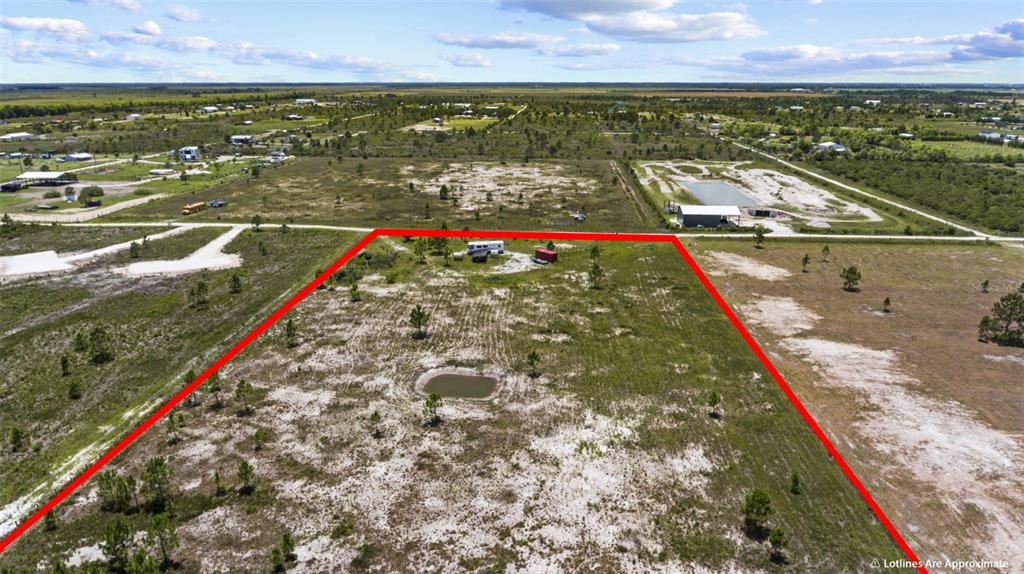 An aerial view shows a large, rectangular plot of land outlined in red with a small pond — 49021 BERMONT ROAD, PUNTA GORDA, FL
