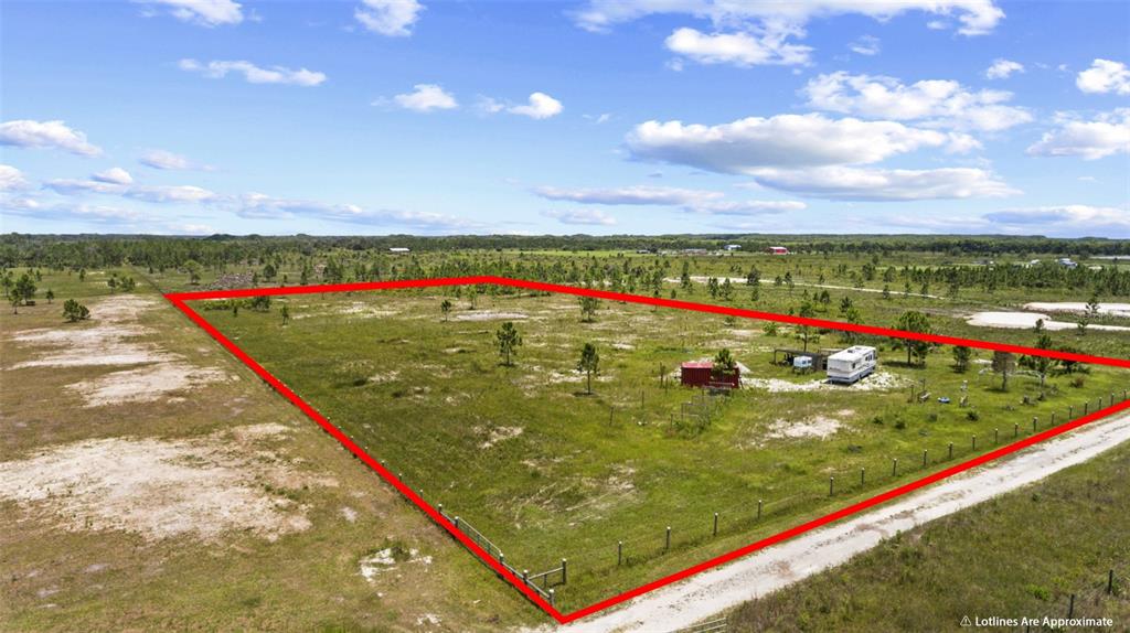 An aerial view shows a fenced, grassy lot with a small shed and a camper — 49021 BERMONT ROAD, PUNTA GORDA, FL