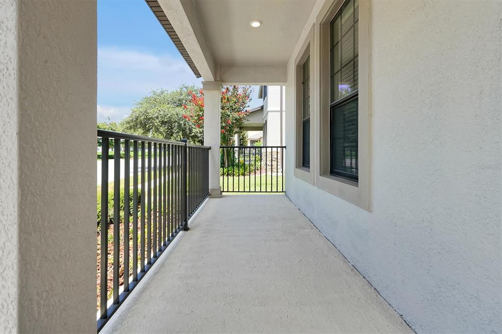 A covered porch features a concrete floor, black metal railings, and a white stucco wall — 15101 PURPLE MARTIN STREET, WINTER GARDEN, FL