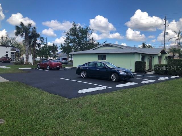 A light green building with a parking lot containing a red car and a dark sedan — 795 CRESTVIEW CIRCLE NW, PORT CHARLOTTE, FL