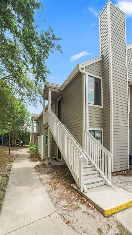 An exterior view of a multi-story apartment building with a wooden staircase leading to a balcony — 537 SUN RIDGE PLACE UNIT 201, ALTAMONTE SPRINGS, FL
