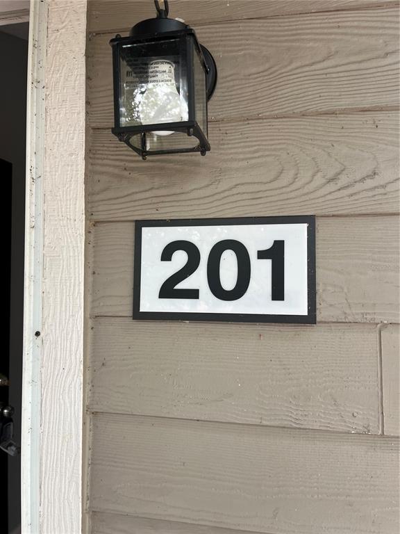 A black house number sign reading 201 is mounted on tan horizontal siding below a light — 537 SUN RIDGE PLACE UNIT 201, ALTAMONTE SPRINGS, FL