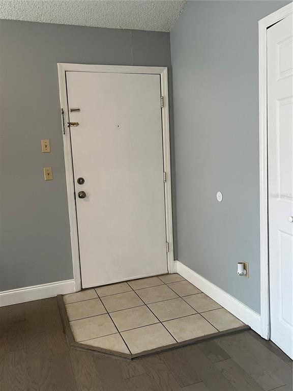 An entryway features a white door, tiled floor transition, and gray walls with wood flooring — 537 SUN RIDGE PLACE UNIT 201, ALTAMONTE SPRINGS, FL