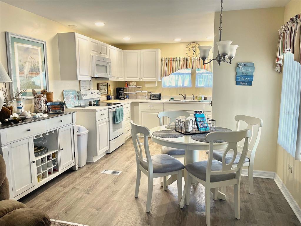 A kitchen with white cabinets, light wood-look flooring, and a round dining table — 9790 66TH STREET UNIT 111, PINELLAS PARK, FL