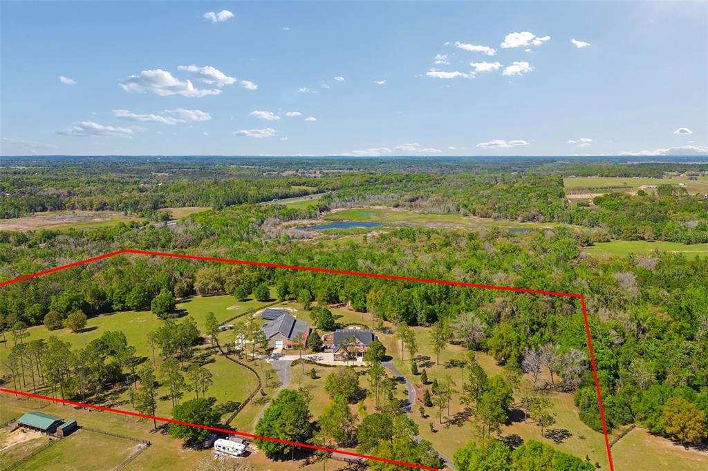 An aerial view shows a large house and barn on a wooded, fenced rural property — 32641 BLUEBERRY HILL WAY, DADE CITY, FL