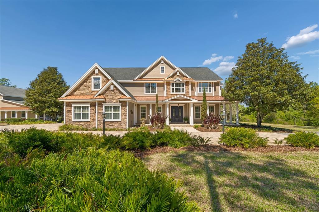 A two-story suburban home features stone and siding exterior with a covered front porch — 32641 BLUEBERRY HILL WAY, DADE CITY, FL