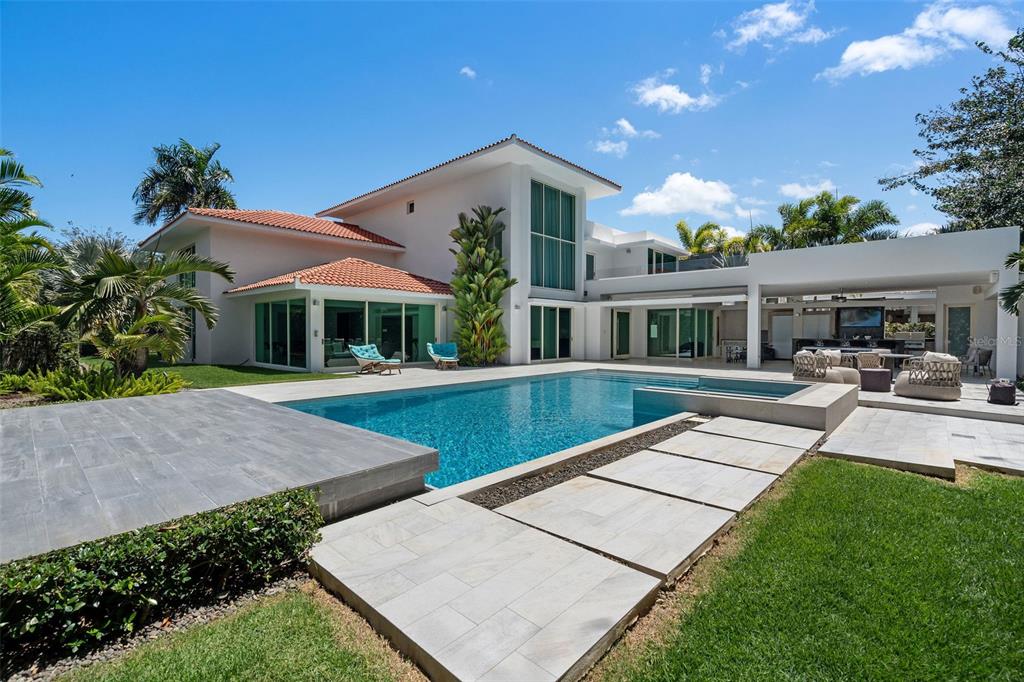 A modern white house features a swimming pool, patio, and landscaped lawn under a blue sky — 336 DORADO BEACH EAST, DORADO, PR