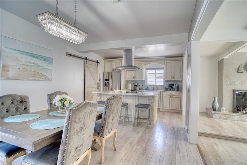 A dining area with a crystal chandelier opens into a kitchen featuring white cabinetry — 2403 W VINA DEL MAR BOULEVARD, ST PETE BEACH, FL