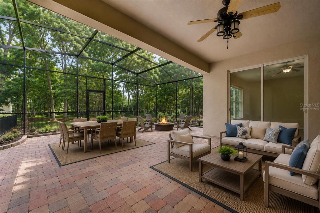 A covered patio with a brick floor, outdoor dining set, fire pit, and seating area — 597 SAND WEDGE LOOP, APOPKA, FL