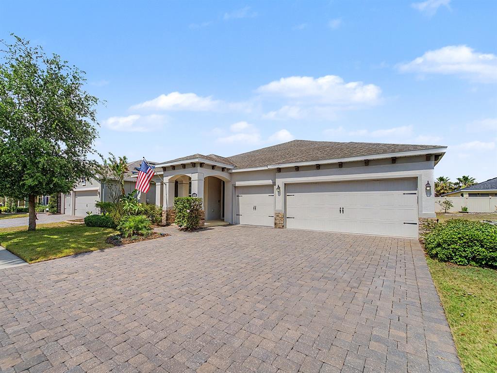 A single-story house with a paved driveway, three-car garage, and an American flag — 11626 LAKE LUCAYA DRIVE, RIVERVIEW, FL