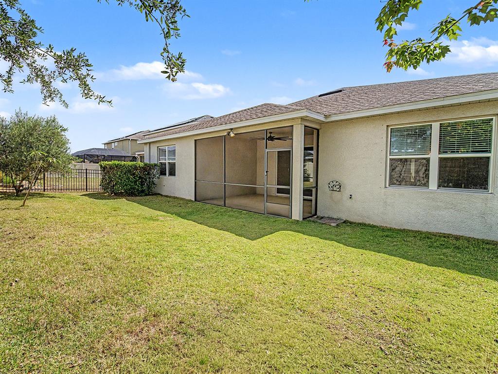 A backyard view of a house with a screened-in patio and a grassy lawn — 11626 LAKE LUCAYA DRIVE, RIVERVIEW, FL