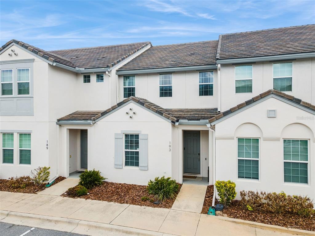 The exterior of a two-story townhouse with a light-colored facade and a tiled roof — 193 CAPTIVA DRIVE, DAVENPORT, FL