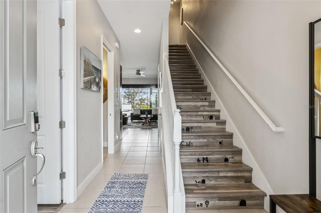 A bright entryway features a staircase with decorative mouse hole decals on the risers — 193 CAPTIVA DRIVE, DAVENPORT, FL